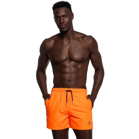 Stylish pose of a person wearing FROG Swim Trunks in Neon Orange, showcasing the bold neon color, convenient pockets, and elastic waistband with drawstrings for a comfortable fit