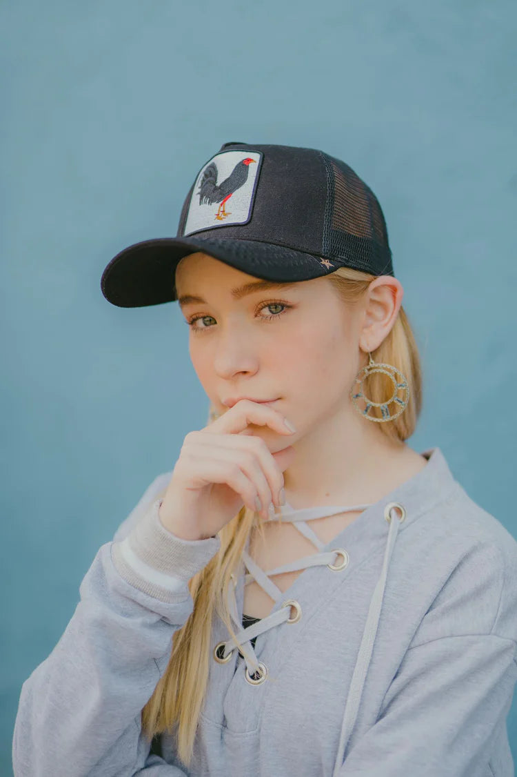 Side view of a woman wearing the Gold Star Rooster Black Trucker Hat, showing off its comfort and breathable mesh design