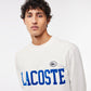 Close-up of a person posing in Lacoste Men's Flocked Fleece Sweatshirt in white, showcasing the premium organic cotton fleece and embroidered crocodile on the breast for a stylish, comfortable look