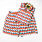 Sunset Alchemy Swim Trunks kept with the matching Sunset Alchemy Short Sleeve Shirt folded, highlighting their vibrant colors and stylish design, perfect for a coordinated summer outfit