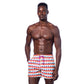 Stylish shot of a man wearing the Sunset Alchemy Swim Trunks without a shirt, showcasing their vibrant colors and modern design, perfect for summer activities like beach volleyball or swimming