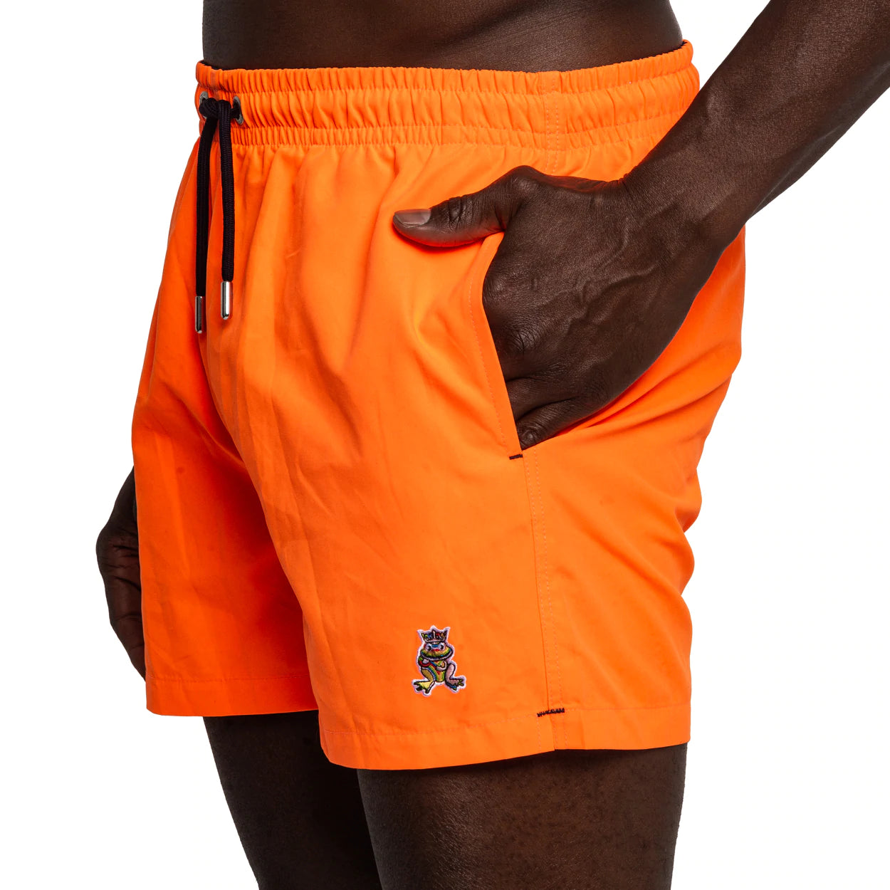 Side view of FROG Swim Trunks in Neon Orange, with the person's hands inside the pocket, highlighting the comfortable fit and above-the-knee length of the swim trunks, perfect for all-day wear