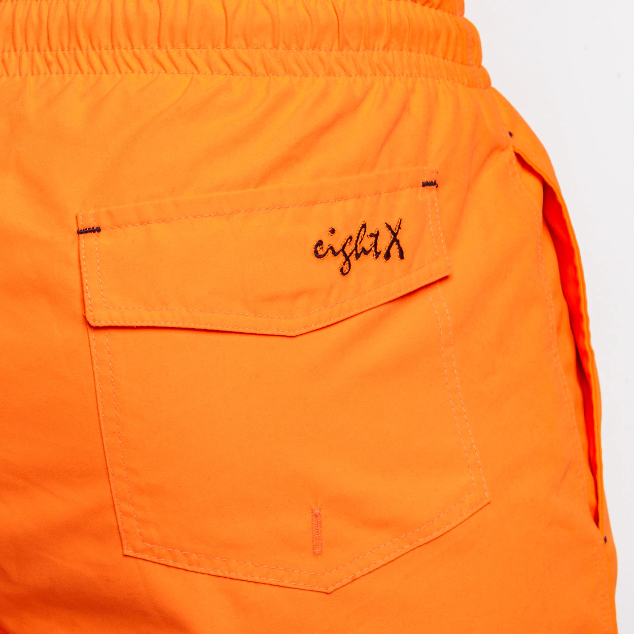 Close-up view of the backside pocket of FROG Swim Trunks in Neon Orange, demonstrating the convenient pocket design for storing gadgets or small essentials while swimming