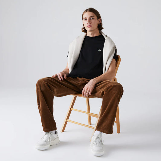 Stylish man sitting in a chair wearing Men's Crew Neck Pima Cotton Jersey T-shirt in vibrant tone, with Lacoste embroidered green crocodile logo on chest